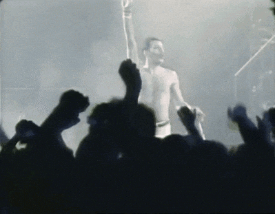 a man is singing into a microphone in front of a crowd .