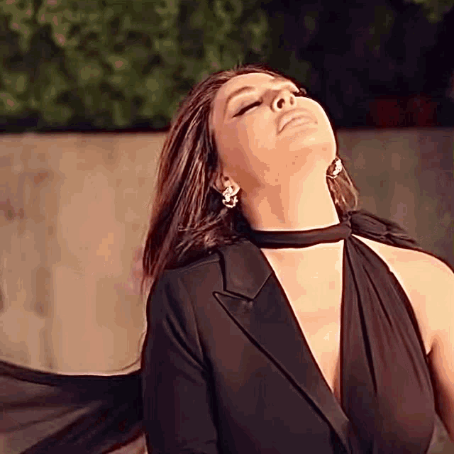 a woman in a black dress with her eyes closed and her hair blowing in the wind .