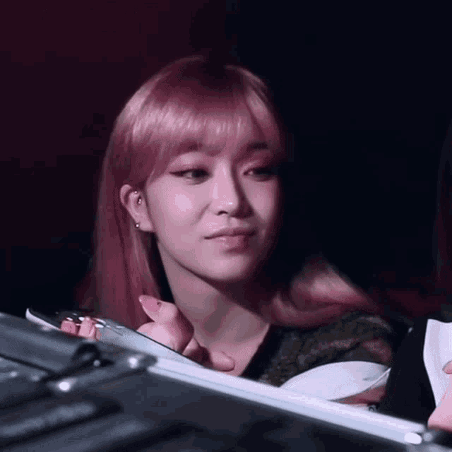 a woman with pink hair is sitting in front of a case
