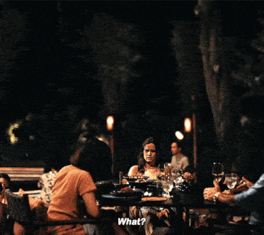 a group of people are sitting at a table and one of them is asking what
