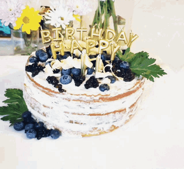 a birthday cake with blueberries and candles that say happy