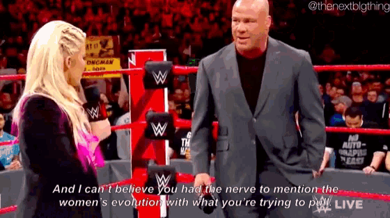 a man in a suit and a woman in a wrestling ring are talking to each other .