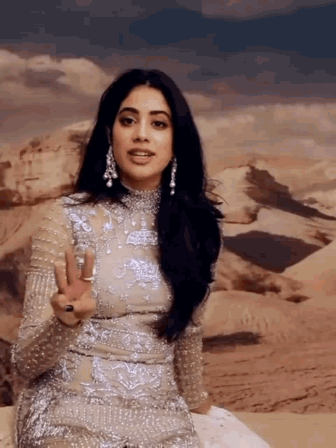 a woman in a white dress is sitting in front of a desert scene