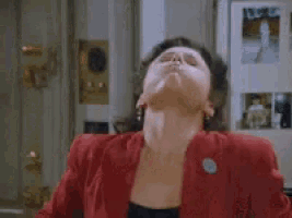 a woman in a red jacket is sitting in front of a refrigerator with her eyes closed .