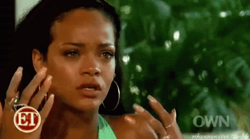 a woman is talking on a cell phone while wearing hoop earrings and a green tank top .