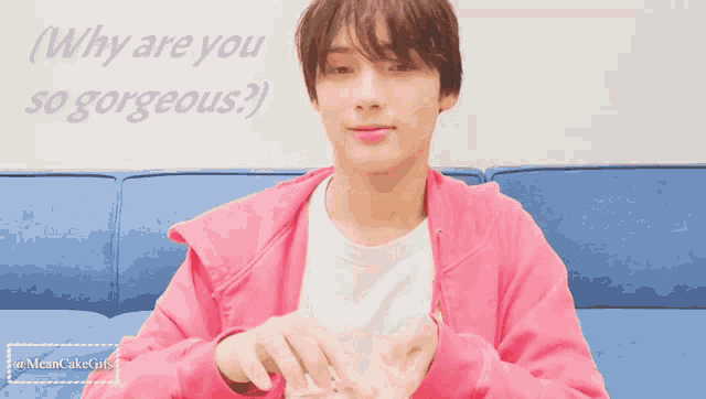 a man in a pink jacket is sitting on a blue couch with the words " why are you so gorgeous " behind him