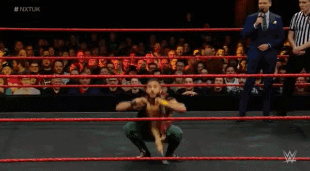 a wrestler is standing in a ring with his arms in the air