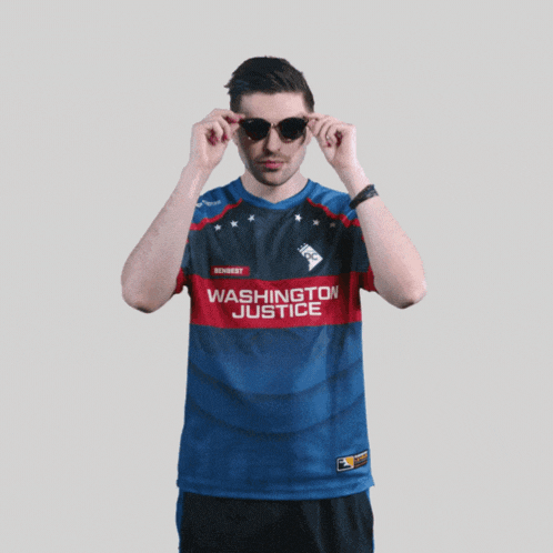 a man wearing a washington justice shirt adjusts his glasses