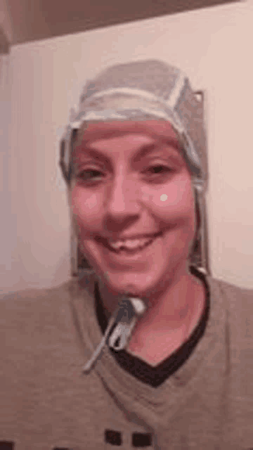a woman is wearing a surgical cap and smiling while holding a toothbrush .