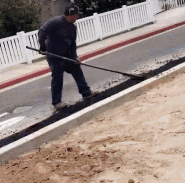 a man wearing headphones is using a shovel to remove dirt from the side of the road .