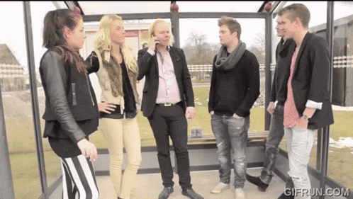 a group of people standing in a bus shelter with gifrun.com in the bottom right corner