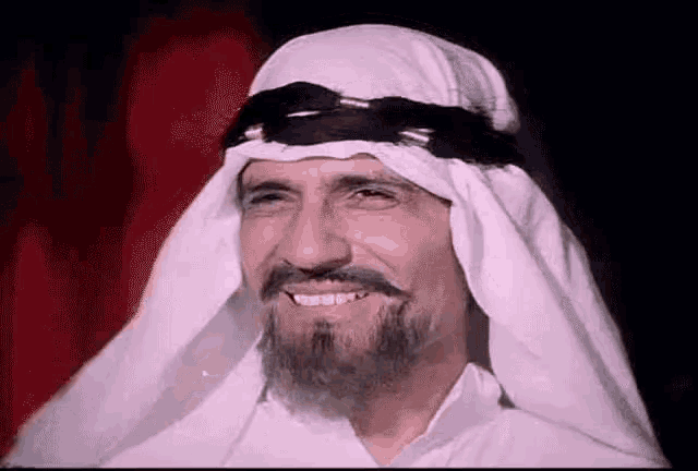 a man with a beard wearing a white turban and smiling .
