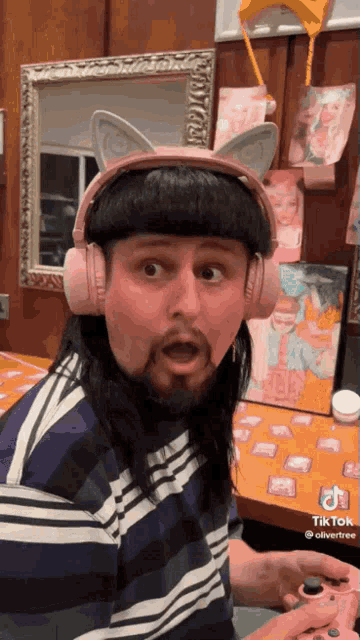 a man wearing pink headphones with cat ears is playing a game