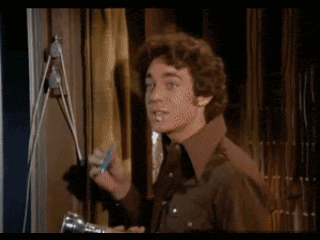 a man in a brown shirt is smoking a cigarette while holding a flashlight