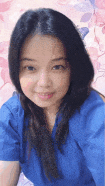 a woman in a blue shirt is smiling with a pink background