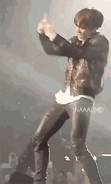 a man in a leather jacket is dancing on stage .