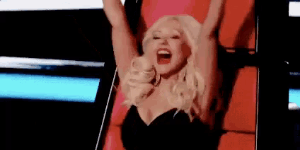 a woman is sitting on a red chair with her arms in the air and screaming .