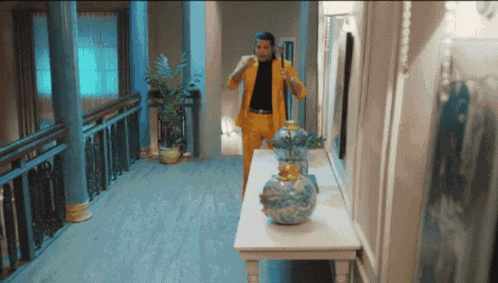 a man in a yellow suit stands in a hallway next to a table