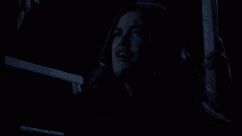 a woman is crying in the dark while holding a railing in a dark room .