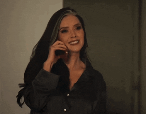 a woman is smiling while talking on her phone