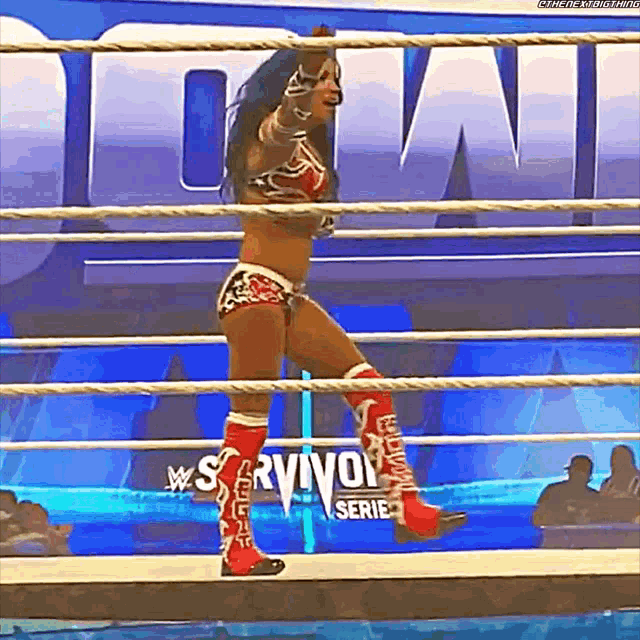 a woman is standing in a wrestling ring with a sign that says survivor series in the background