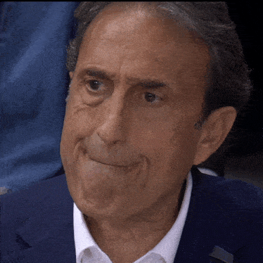 a man wearing a blue suit and white shirt makes a funny face