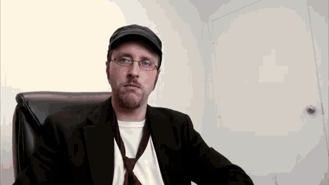 a man wearing glasses and a hat sitting in a chair
