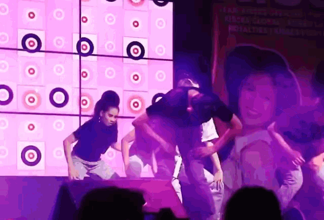 a group of people are dancing on a stage in front of a large screen that says target