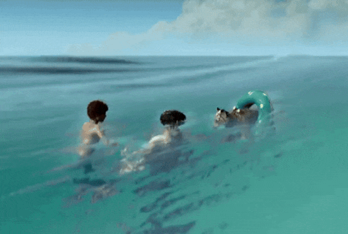 two men are swimming in the ocean with a dog in the background