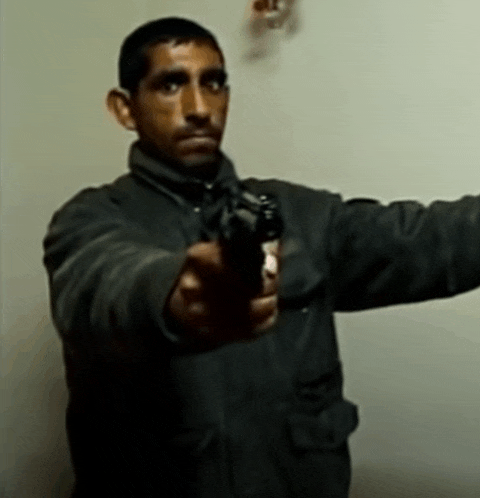 a man in a black jacket holds a gun in his right hand