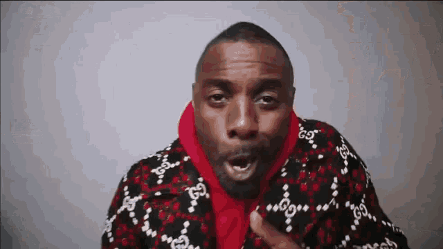 a man in a red hoodie is making a funny face while wearing a black and red sweater .