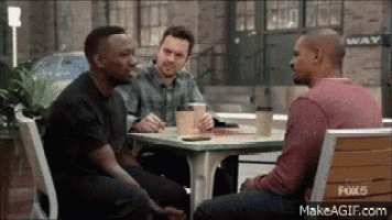 a group of men are sitting at a table talking .