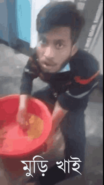 a man is kneeling down holding a red bucket with a foreign language on it .