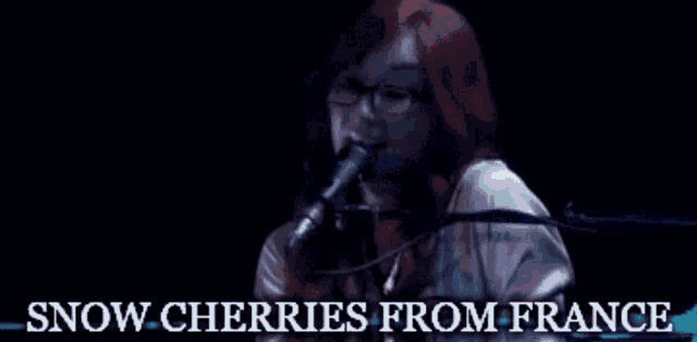 a woman singing into a microphone with the words " snow cherries from france " below her