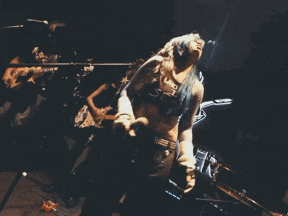 a woman with blue hair is singing into a microphone while a man plays a guitar