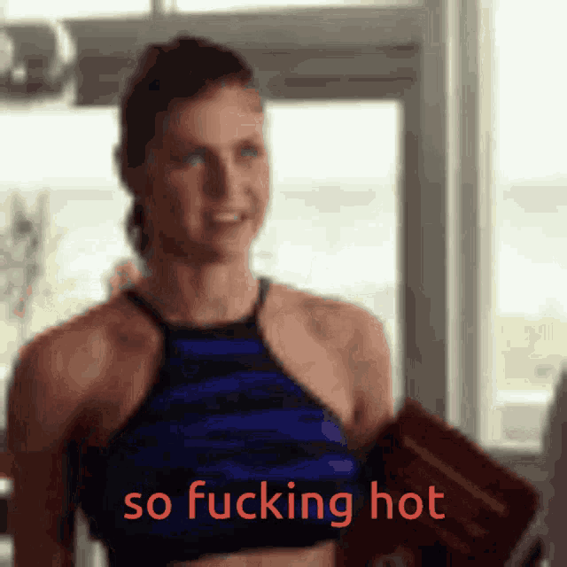 a woman in a blue top is holding a book that says so fucking hot in red letters