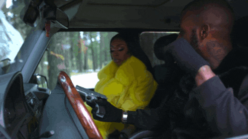 a man is holding a gun while a woman in a yellow coat sits in a car