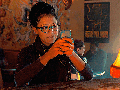 a woman with glasses is looking at her phone
