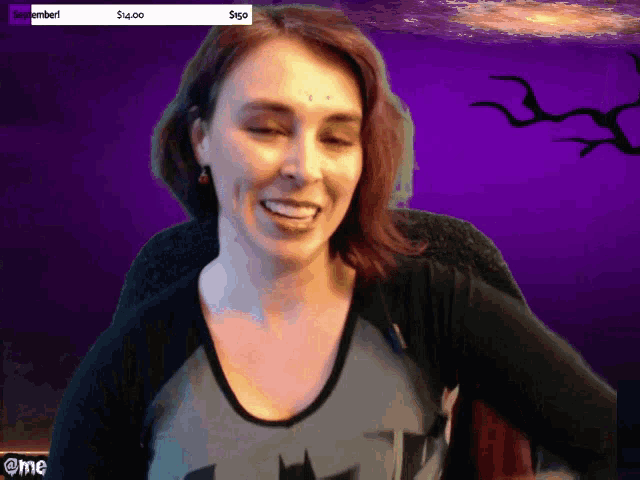 a woman in a batman shirt is smiling in front of a streamer screen