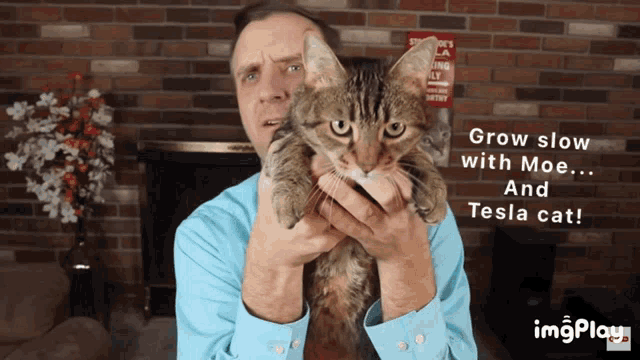 a man is holding a cat with the words grow slow with moe ... and tesla cat