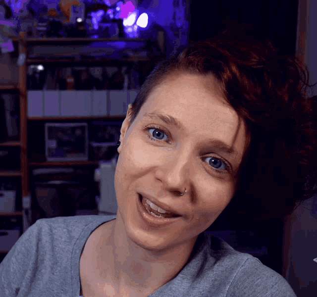 a woman with blue eyes and a nose ring is smiling
