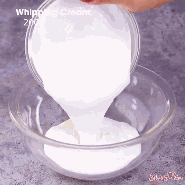 a person is pouring whipping cream into a clear bowl
