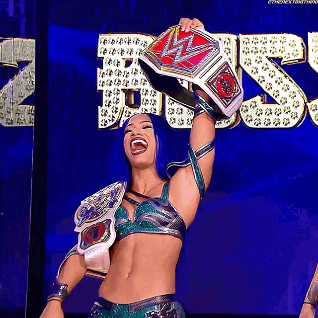 a woman with blue hair is holding a wrestling championship belt over her head
