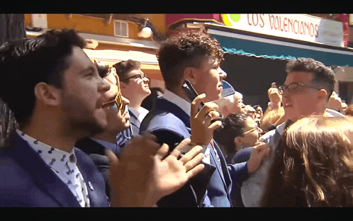 a group of people applauding in front of a sign that says los volenculos