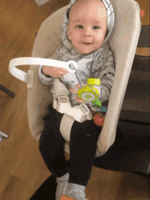a baby is sitting in a high chair with a toy in his hand