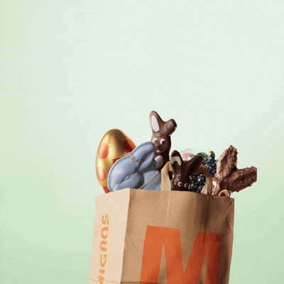 a brown bag with the letter m on it is filled with chocolate bunnies and eggs