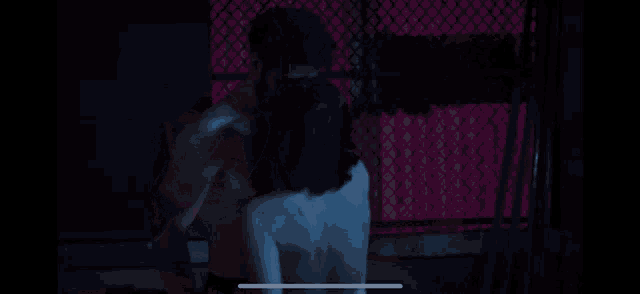 a man without a shirt is being hugged by a woman in a dark room