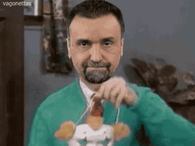 a man in a green jacket and tie is holding a stuffed animal .