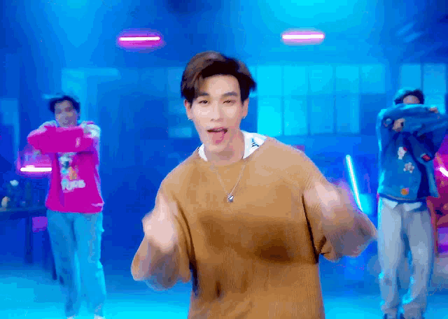a man in a brown sweater is dancing in front of a group of people .