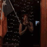 a woman is singing into a microphone while holding a texas flag